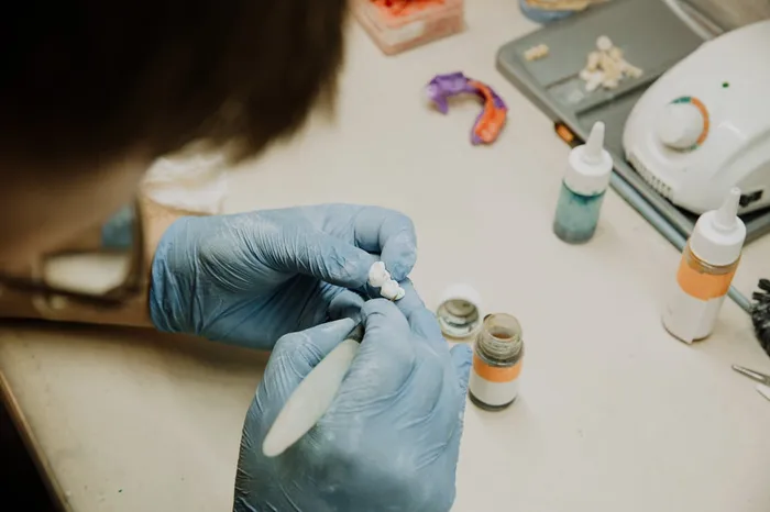 Dental laboratory technician crafting a prosthetic crown by hand — the skilled craftsmanship behind the quality of restorations at safe, accredited Turkish dental clinics